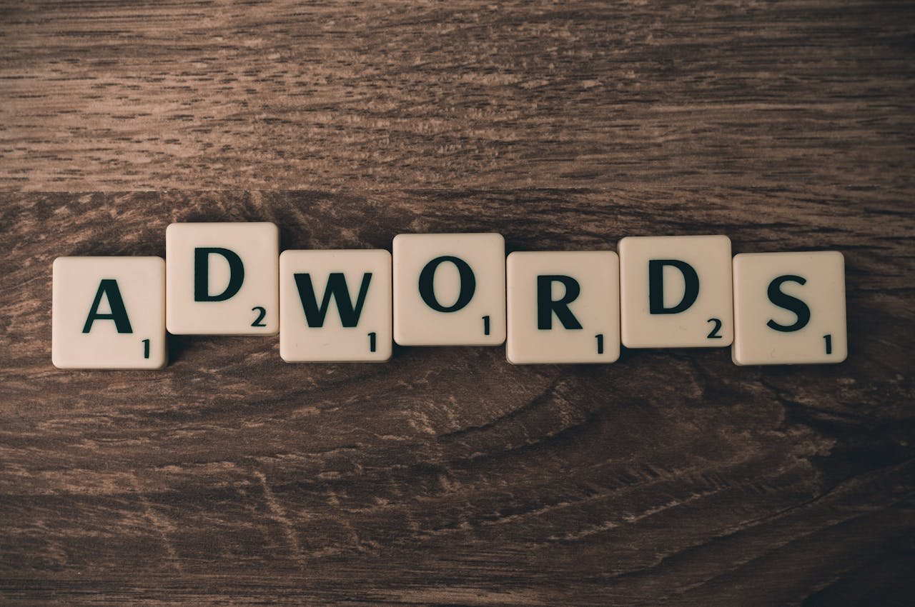 Scrabble tiles spelling 'AdWords' on a wooden surface, symbolizing digital marketing concepts.