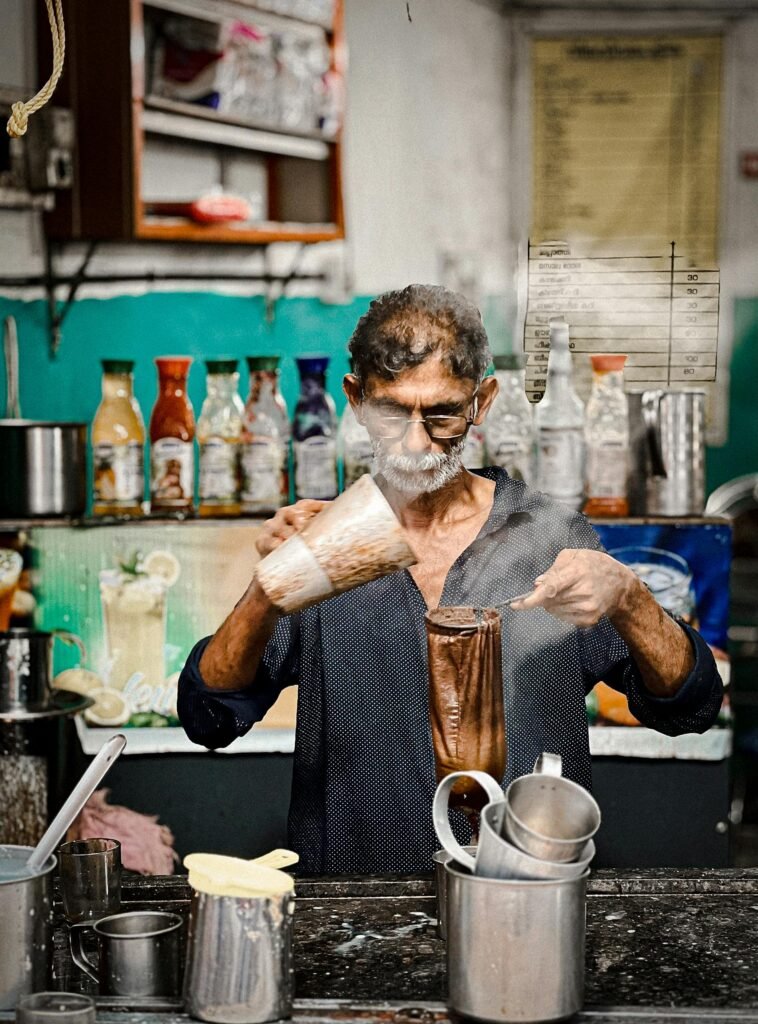 An Indian man skillfully making traditional chai in a vibrant Kottayam cafe. Go Digital Quick